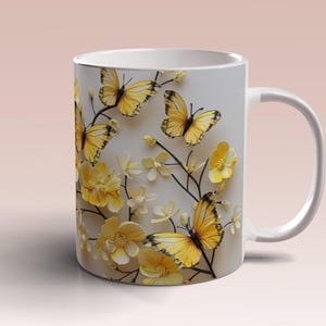 Puede incluir: Taza de cerámica blanca con un diseño de mariposas amarillas y flores. Las mariposas tienen marcas negras en sus alas.