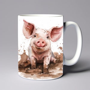 May include: White ceramic mug featuring a watercolor illustration of a smiling pig in mud. The pig is pink with large ears and a muddy snout. Brown paint splatters surround the pig, and the mug has a white handle.