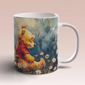 May include: A white ceramic mug featuring a watercolour illustration of Winnie the Pooh sitting in a field of flowers. The illustration is in shades of blue, green, yellow, and brown.