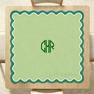May include: A square, light green placemat with a scalloped edge design. The border is dark green with a white inner edge. The center features a green monogram of the letters "CHR". The text "T.S. Art Supplies" is at the bottom.