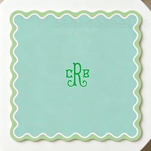 May include: A square, mint green placemat with a scalloped edge in white and light green. The center features a green monogram with the letters CRB.