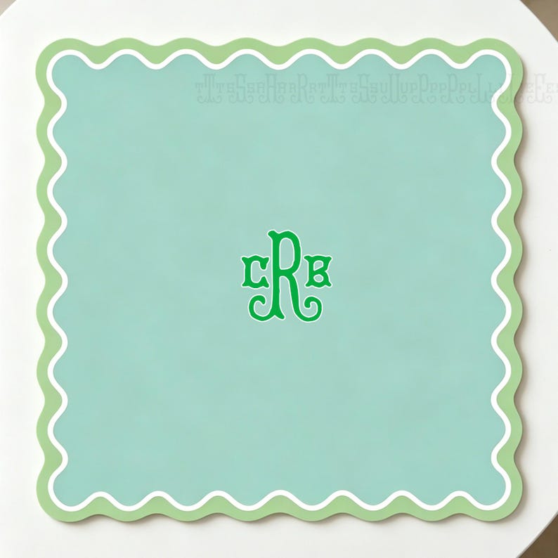 May include: A square, mint green placemat with a scalloped edge in white and light green. The center features a green monogram with the letters CRB.