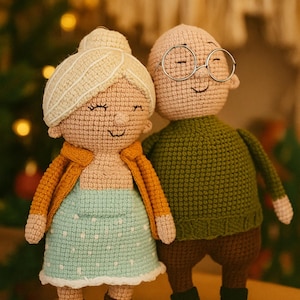 May include: Crocheted dolls of an elderly couple. The woman doll wears a light blue dress with white polka dots and an orange jacket. The man doll wears a green sweater and glasses. The dolls are handmade and have smiling faces.