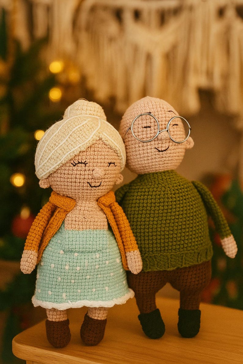 May include: Crocheted dolls of an elderly couple. The woman doll wears a light blue dress with white polka dots and an orange jacket. The man doll wears a green sweater and glasses. The dolls are handmade and have smiling faces.
