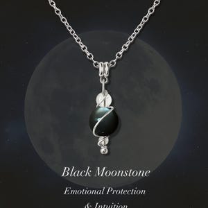 May include: A silver necklace with a black moonstone pendant. The pendant is a dark sphere wrapped in silver wire, with a smaller white stone above and below. The text reads "Black Moonstone, Emotional Protection & Intuition."