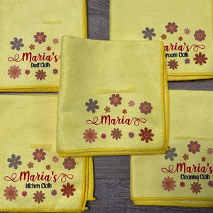 May include: Five yellow cleaning cloths with embroidered floral designs and the text "Maria's" with different descriptions for each cloth: "Dust Cloth", "Kitchen Cloth", "Cleaning Cloth", "Bathroom Cloth", and "Maria".
