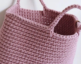 Hangmand in stoffig roze, geweven opbergmand met vakjes.