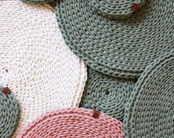 Può includere: Una collezione di tovagliette e sottobicchieri circolari all'uncinetto fatti a mano in vari colori. Le tovagliette e i sottobicchieri sono nelle tonalità verde salvia, crema e rosa antico. Ogni pezzo ha un design a spirale e una piccola etichetta in pelle marrone.