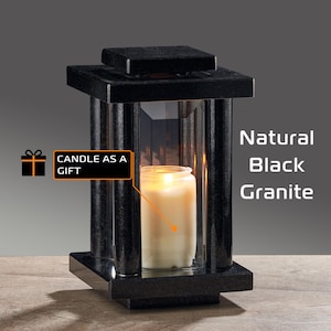 Peut inclure: Une lanterne à bougie en granit noir avec une bougie allumée à l'intérieur. La lanterne a un dessus et une base carrés, avec des supports verticaux et des panneaux de verre transparents. Le texte sur l'image indique "Candle as a Gift" et "Natural Black Granite."