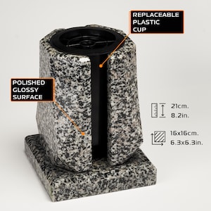 Puede incluir: Un jarrón de granito con una superficie pulida y brillante. El jarrón tiene una copa de plástico reemplazable y mide 21 cm de alto y 16 cm x 16 cm en la base. El jarrón tiene un diseño único y moderno.