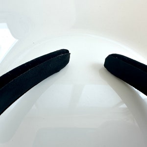 May include: A black headband with a smooth, slightly textured surface.