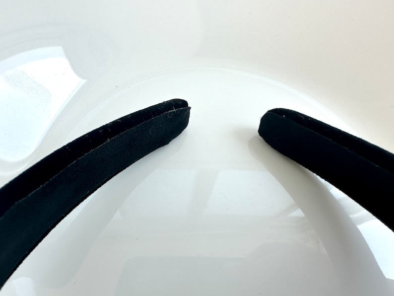 May include: A black headband with a smooth, slightly textured surface.