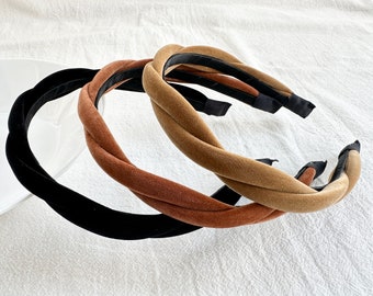 Puede incluir: Tres diademas de terciopelo en negro, marrón y beige. Las diademas están retorcidas y tienen una textura suave y aterciopelada.