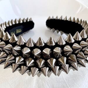 May include: A silver headband with a black velvet band and rows of silver spikes. The headband is a fashion accessory.