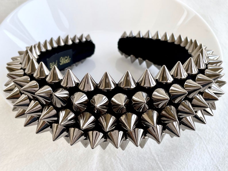May include: A silver headband with a black velvet band and rows of silver spikes. The headband is a fashion accessory.