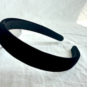 May include: A black velvet headband. The headband is wide and has a smooth, soft texture.