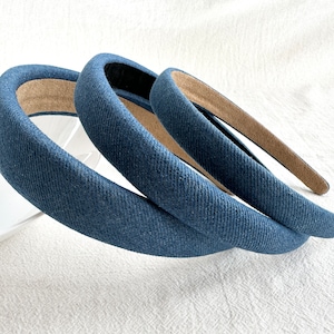 May include: Three blue denim headbands with a brown fabric lining. The headbands are stacked on top of each other.