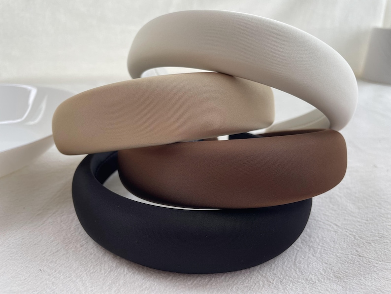 K&ouml;nnte beinhalten: Vier Stoff-Haarband in einem Stapel. Das oberste Haarband ist wei&szlig;, das zweite ist beige, das dritte ist braun und das unterste Haarband ist schwarz.
