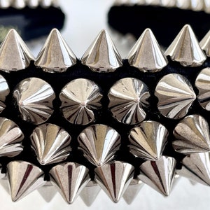 May include: A black headband with silver metal spikes. The spikes are arranged in rows and point upwards.