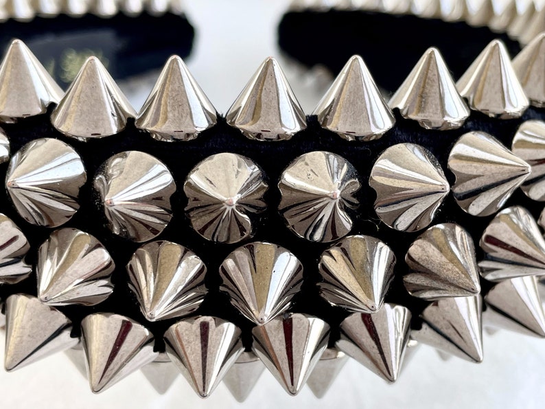 May include: A black headband with silver metal spikes. The spikes are arranged in rows and point upwards.