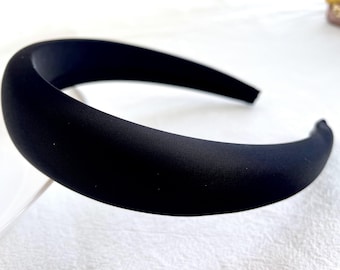 Könnte beinhalten: Ein schwarzes Samt-Haarband. Das Haarband ist breit und hat eine glatte, matte Oberfläche.