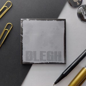 Peut inclure: Un bloc-notes adhésif gris avec une bordure noire et le mot "BLEGH" imprimé en lettres noires.