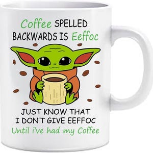 May include: A white ceramic mug featuring a green cartoon character with large eyes holding a tan cup. The text reads: Coffee SPELLED BACKWARDS IS Eeffoc JUST KNOW THAT I DON'T GIVE EEFFOC Until i've had my Coffee. Brown coffee beans are scattered around.