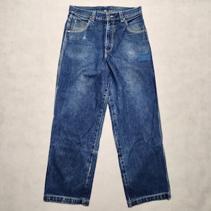 May include: Blue denim jeans with a faded wash and a small embroidered logo on the right leg.