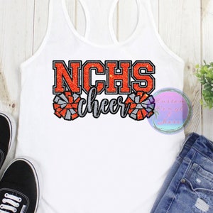 May include: A white racerback tank top featuring a graphic print with the text NCHS in orange glitter, the word cheer in silver glitter, and two pom-pom illustrations in orange and silver glitter. The design is centered on the front of the shirt.