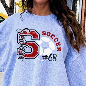 May include: Gray sweatshirt with a red glitter letter S, a soccer ball, and the text "Strikers" and "Soccer #68".