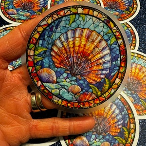 May include: A set of round stickers featuring a colorful stained glass design of a seashell with blue, orange, and green accents.