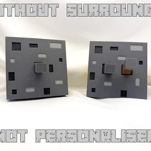 May include: Two grey square display stands with various cut-out shapes and a central cube. The stands have the text "WITHOUT SURROUNDS" and "NOT PERSONALISED" in a pixelated font.