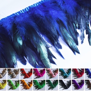 May include: Close-up of a blue feather trim with a braided edge. The feathers transition from a deep blue to a teal color. A selection of other colored feather trims are displayed below, including brown, red, and green.
