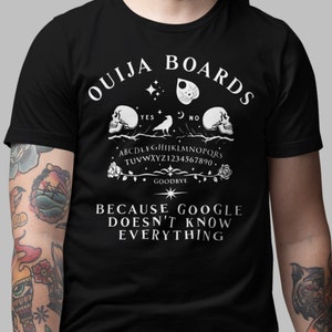 May include: Black t-shirt with a white graphic of an Ouija board with the text "Ouija Boards Because Google Doesn't Know Everything".