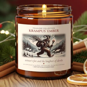 Peut inclure: Une bougie en pot de verre allumée de la collection Folklore, intitulée "Krampus' Ember". L'étiquette présente une illustration de Krampus dans un paysage enneigé. Le texte "winter's fire and the laughter of devils" est également visible.