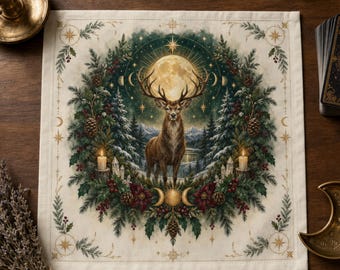 May include: A square fabric altar cloth featuring a central illustration of a deer standing in a snowy forest under a large full moon. The scene is framed by a wreath of pine branches, pinecones, red berries, and two lit candles.