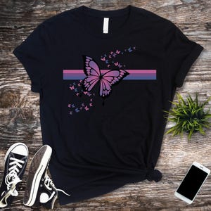 May include: Black t-shirt with a pink and blue butterfly graphic and a thin horizontal stripe in the colors of the bisexual pride flag.