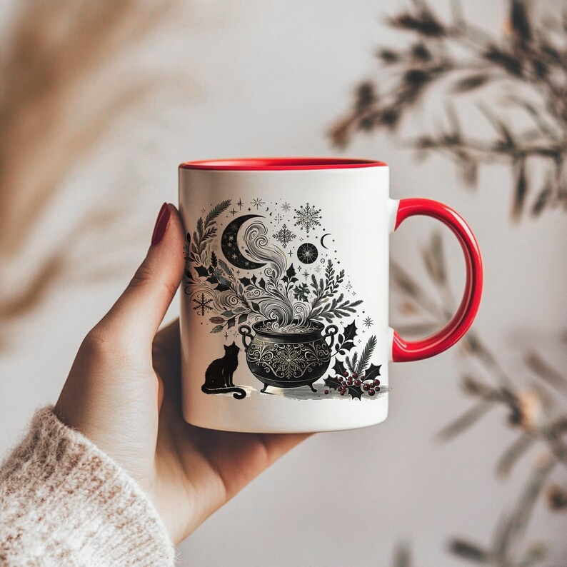 Op de afbeelding: Witte keramische mok met een rode binnenkant en oor. De mok heeft een zwart-wit illustratie van een ketel met stoom, een maan, sneeuwvlokken en een zwarte kat. Het ontwerp heeft een grillig, magisch thema.