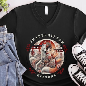 May include: Black V-neck t-shirt featuring a circular graphic with the text "SHAPESHIFTER KITSUNE". The graphic depicts a white and red fox-like creature with a woman in traditional Japanese attire, set against a red gate background.