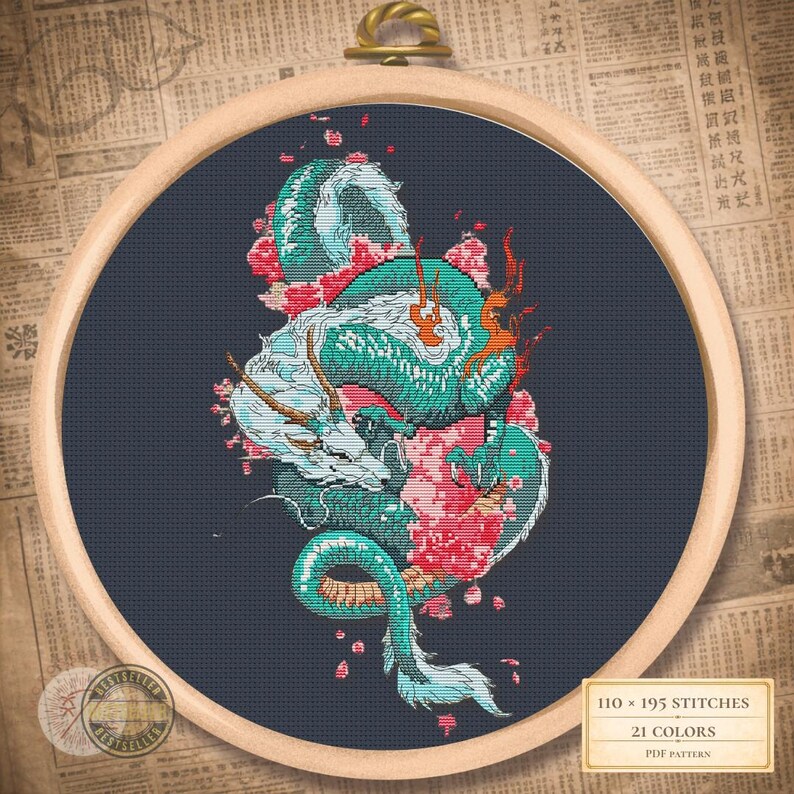May include: Cross-stitch design featuring a teal and white dragon with red accents and pink flowers, set against a dark blue backdrop. The artwork is framed in a wooden embroidery hoop. The image text reads "110 x 195 stitches" and "21 colours".