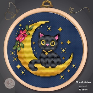 Peut inclure: Un motif de point de croix dans un cercle à broder en bois représentant un chat noir assis sur un croissant de lune jaune sur fond bleu foncé. La lune est ornée de fleurs roses et d'étoiles jaunes. Le texte indique 77 x 69 points et 12 couleurs.