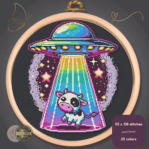 Può includere: Un ricamo a punto croce in un telaio di legno raffigura un UFO che irradia una mucca. L'UFO è blu, viola e verde, con un raggio arcobaleno. La mucca è bianca e nera. Il testo recita "113 x 138 punti" e "25 colori".