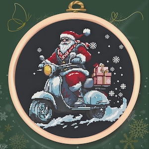 Puede incluir: Bordado de punto de cruz de Papá Noel montado en una scooter azul claro, entregando regalos. Papá Noel lleva un traje rojo, gafas de sol y barba blanca. El fondo es gris oscuro con copos de nieve, en un bastidor de bordado de madera.