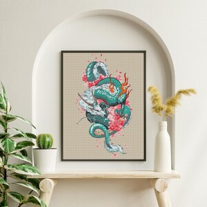 May include: A framed print depicting a teal and white dragon entwined with pink cherry blossoms. The dragon has fiery orange accents against a beige backdrop. The artwork is displayed on a wooden shelf.