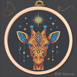 Op de afbeelding: Kruissteekpatroon van een giraffekop, met ingewikkelde geometrische ontwerpen in oranje, blauw en geel. De giraffe staat tegen een donkergrijze achtergrond in een houten borduurring. De tekst "PDF Pattern" is zichtbaar.