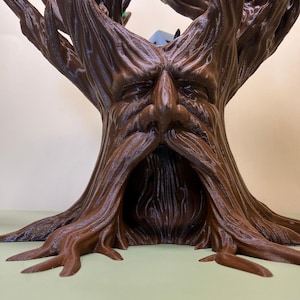 Pu&ograve; includere: Scultura a forma di albero marrone stampata in 3D con un volto scolpito nel tronco. La scultura presenta una superficie dettagliata e strutturata, con il volto caratterizzato da un naso e una barba prominenti. I rami dell'albero si estendono verso l'alto.