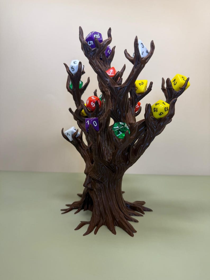 Pu&ograve; includere: Un porta dadi a forma di albero marrone con pi&ugrave; rami, ognuno dei quali tiene un dado colorato. I dadi sono di vari colori, tra cui viola, rosso, giallo, verde e bianco. L'albero ha un volto scolpito sul tronco.