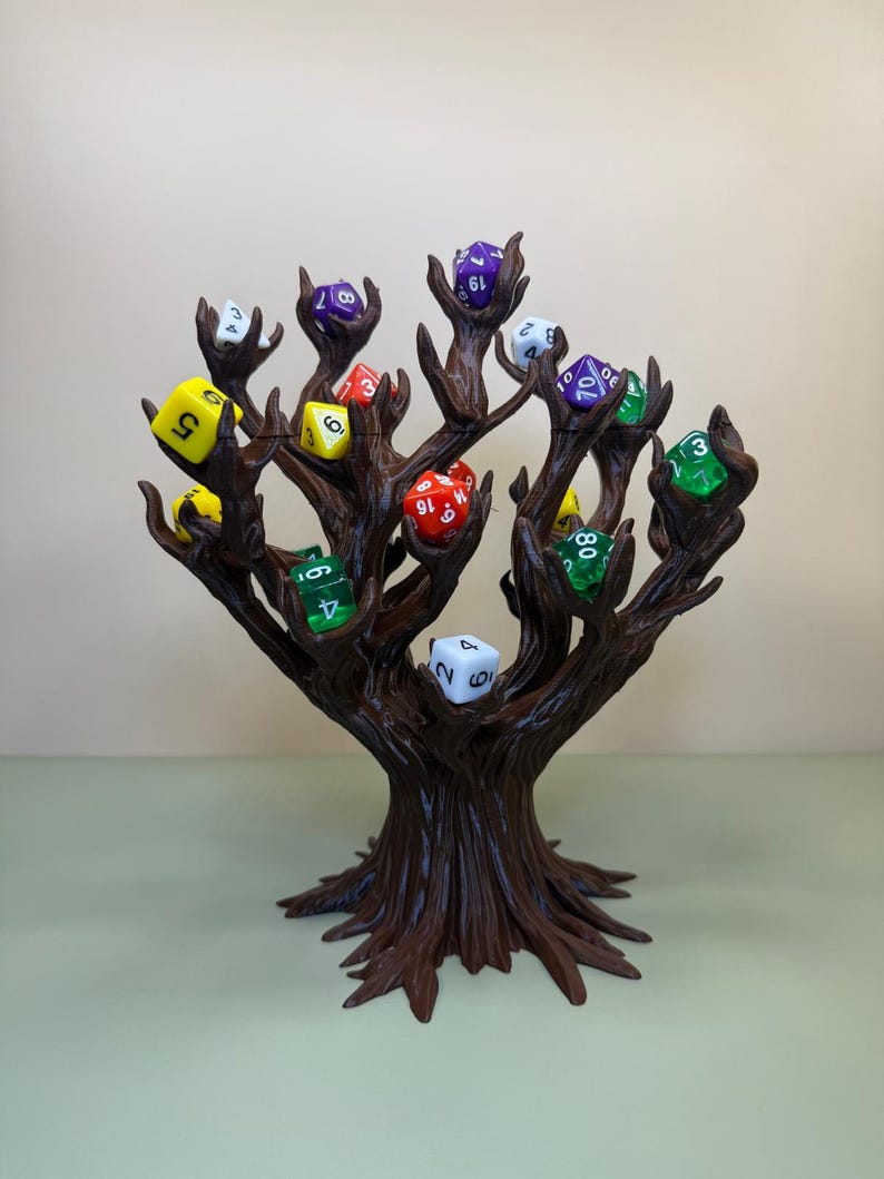 Pu&ograve; includere: Un porta dadi a forma di albero marrone con pi&ugrave; rami, ognuno dei quali tiene un dado a pi&ugrave; facce. I dadi sono di vari colori, tra cui giallo, verde, rosso e viola. Il supporto &egrave; progettato per esporre e conservare i dadi.