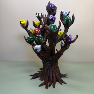 Pu&ograve; includere: Un porta dadi a forma di albero marrone con pi&ugrave; rami, ognuno dei quali tiene un dado colorato. I dadi sono di vari colori, tra cui verde, giallo, rosso e viola. Il supporto &egrave; realizzato in un materiale marrone scuro.
