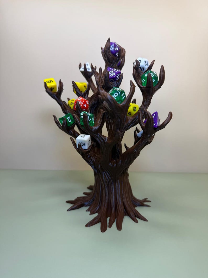Pu&ograve; includere: Un porta dadi a forma di albero marrone con pi&ugrave; rami, ognuno dei quali tiene un dado colorato. I dadi sono di vari colori, tra cui verde, giallo, rosso e viola. Il supporto &egrave; realizzato in un materiale marrone scuro.